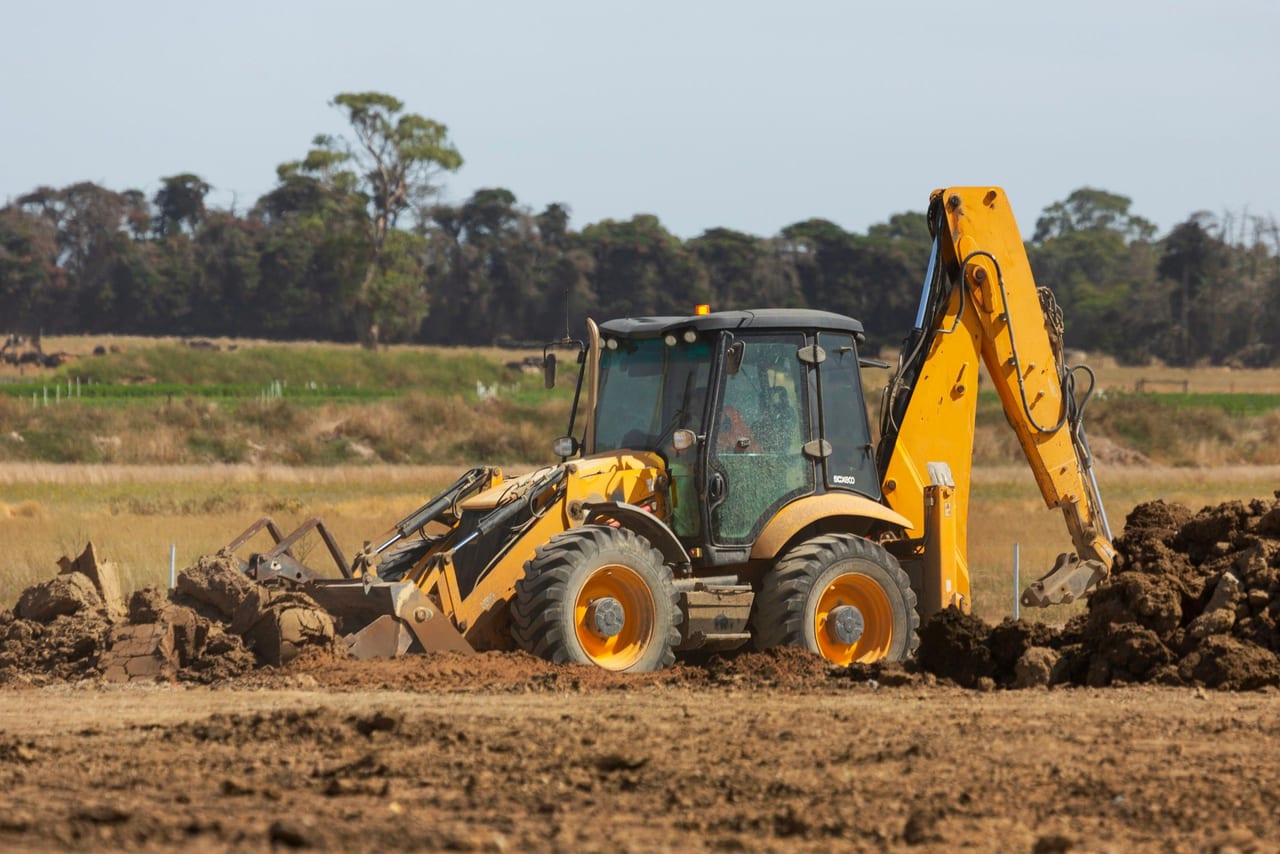 Retroexcavadora amarilla moviendo tierra en un terreno