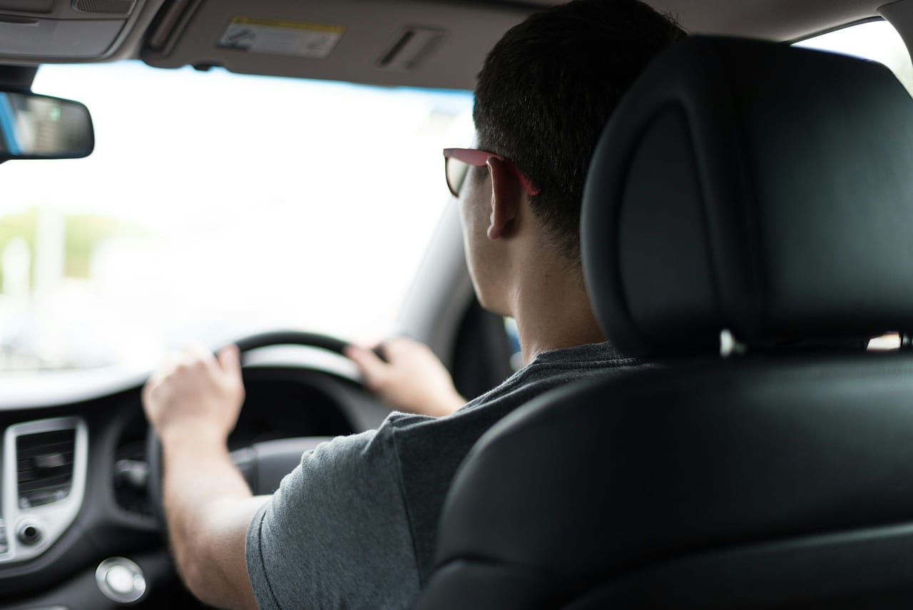 Conductor de espaldas con las manos en el volante