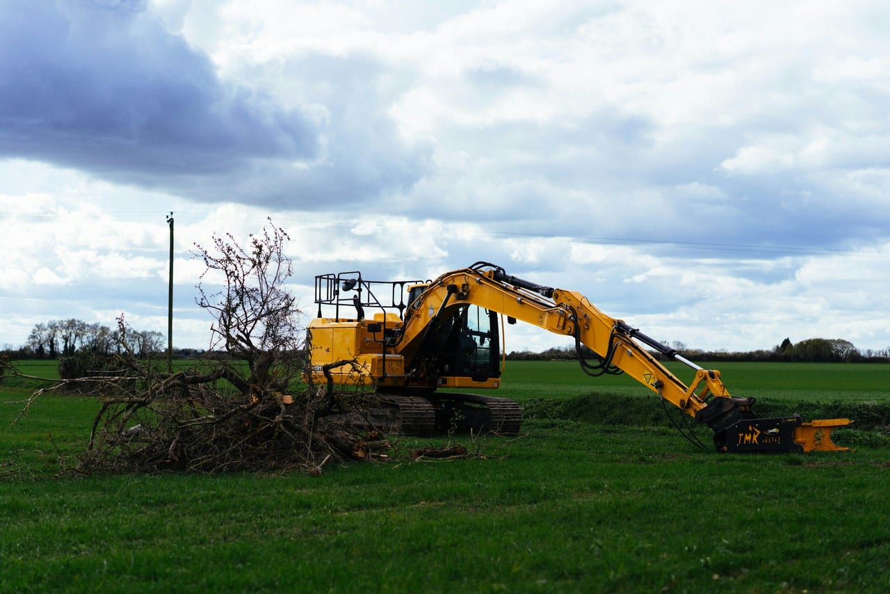 Excavadora amarilla trabajando en un campo verde