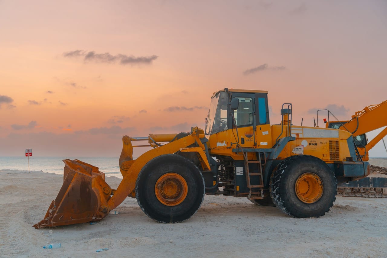 Cargador frontal amarillo en una obra al atardecer